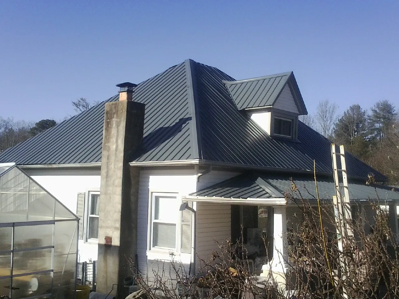 Dark blue standing seam metal roof on a white farmhouse with dormer — Slate & Tile Roof Repair by Roofing Brothers in Harrington Park