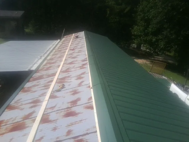 Old rusted panels beside newly installed green metal roofing — Wind Damage Roof Repair by Roofing Brothers in Harrington Park