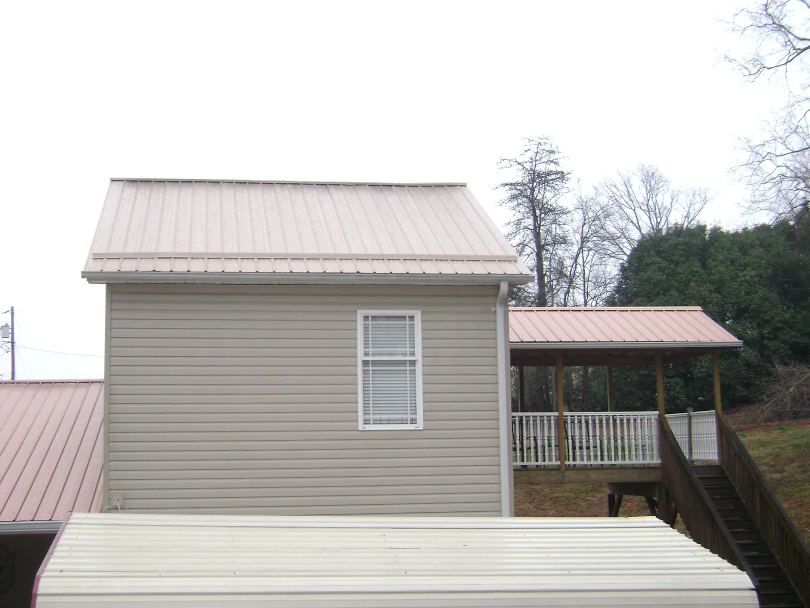 Tan metal roofs on a two story addition and attached porch, from a Roof Replacement job in Harrington Park