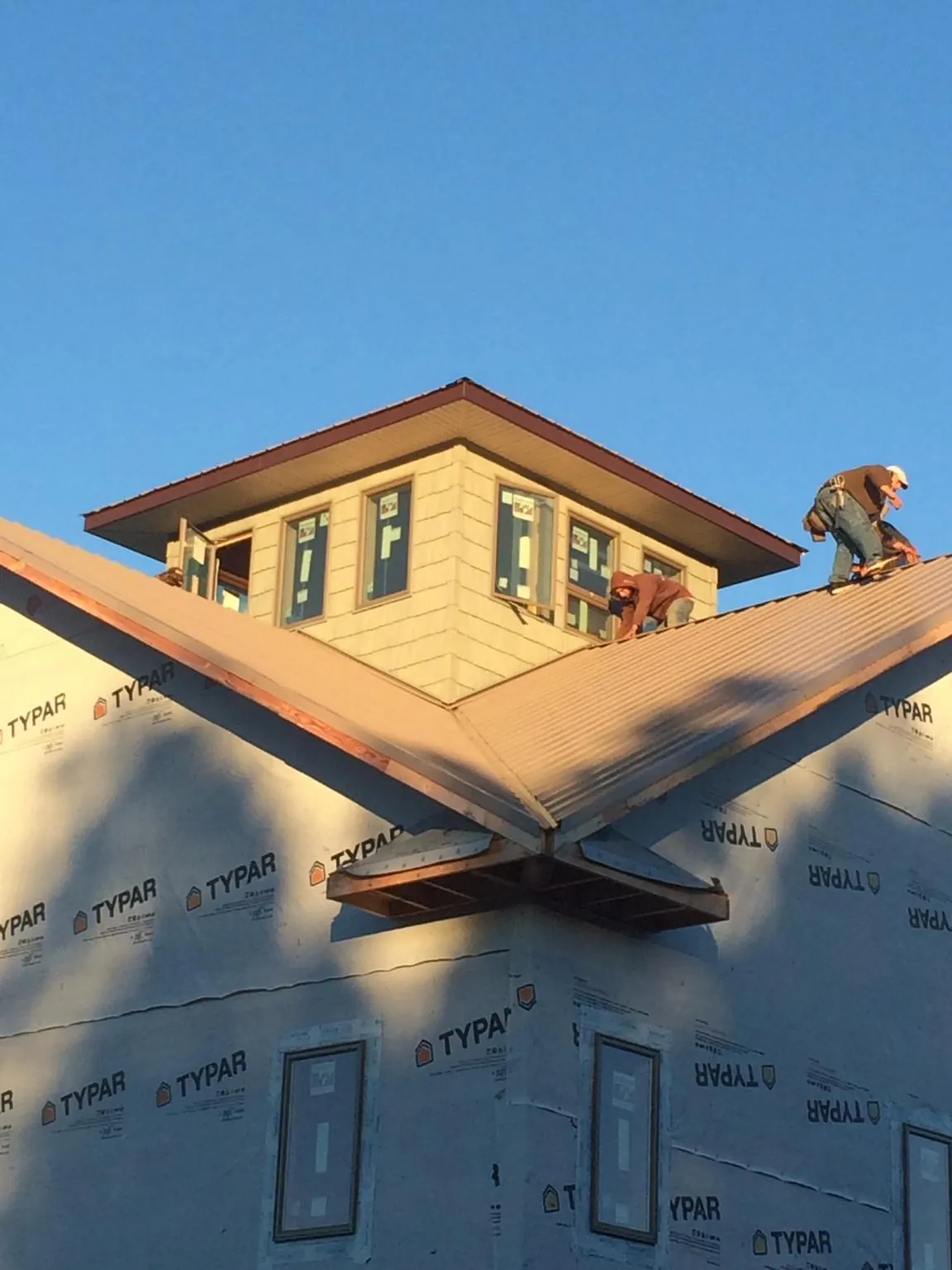 Roofers working around a rooftop cupola on a new metal roof at sunset — Roof Waterproofing in Harrington Park by Roofing Brothers